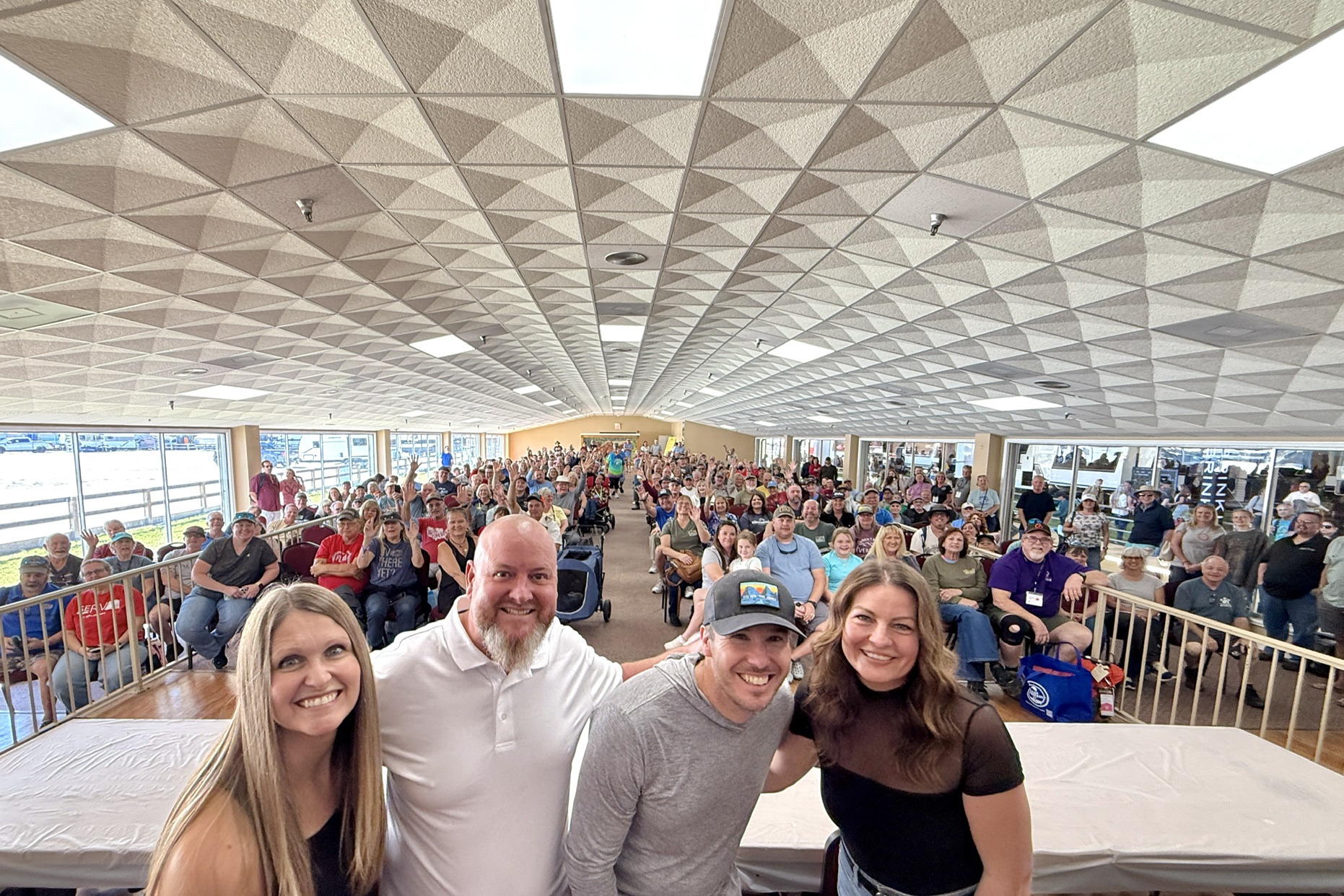 Tampa Campout hosts on stage with the full crowd waving behind them